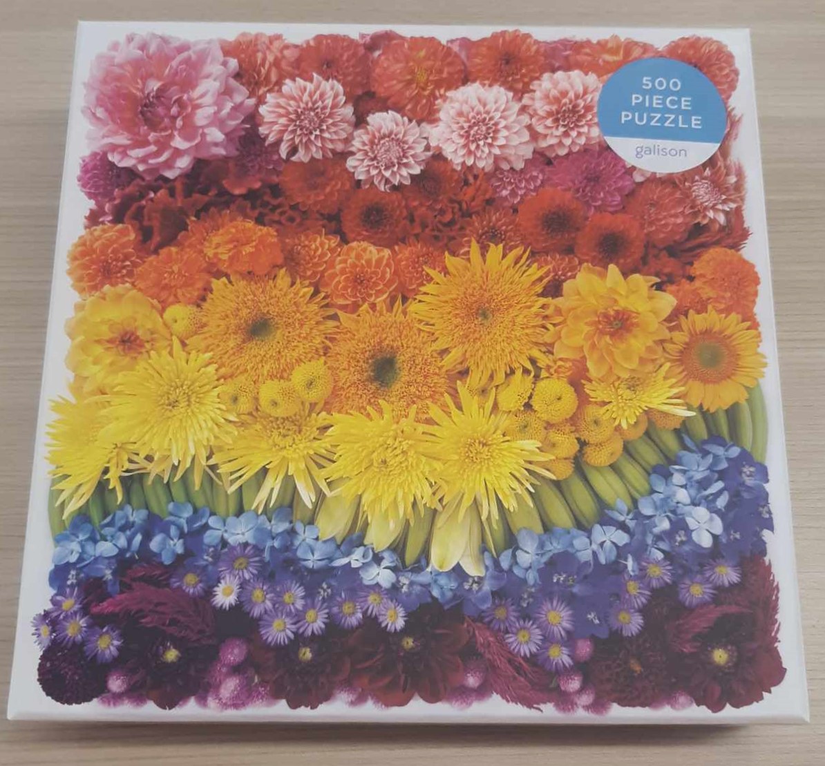 Image of a puzzle cover titled "Flowers" Showing rows of flowers organized in rainbow order.