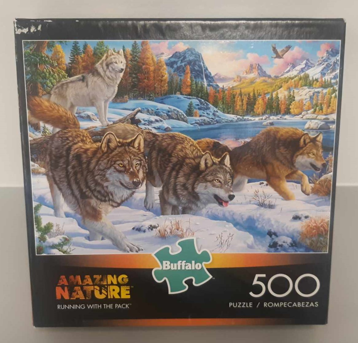 Image of puzzle cover titled "Running with the Pack" that shows multiple wolves that appear to be chasing something near a lakeside.