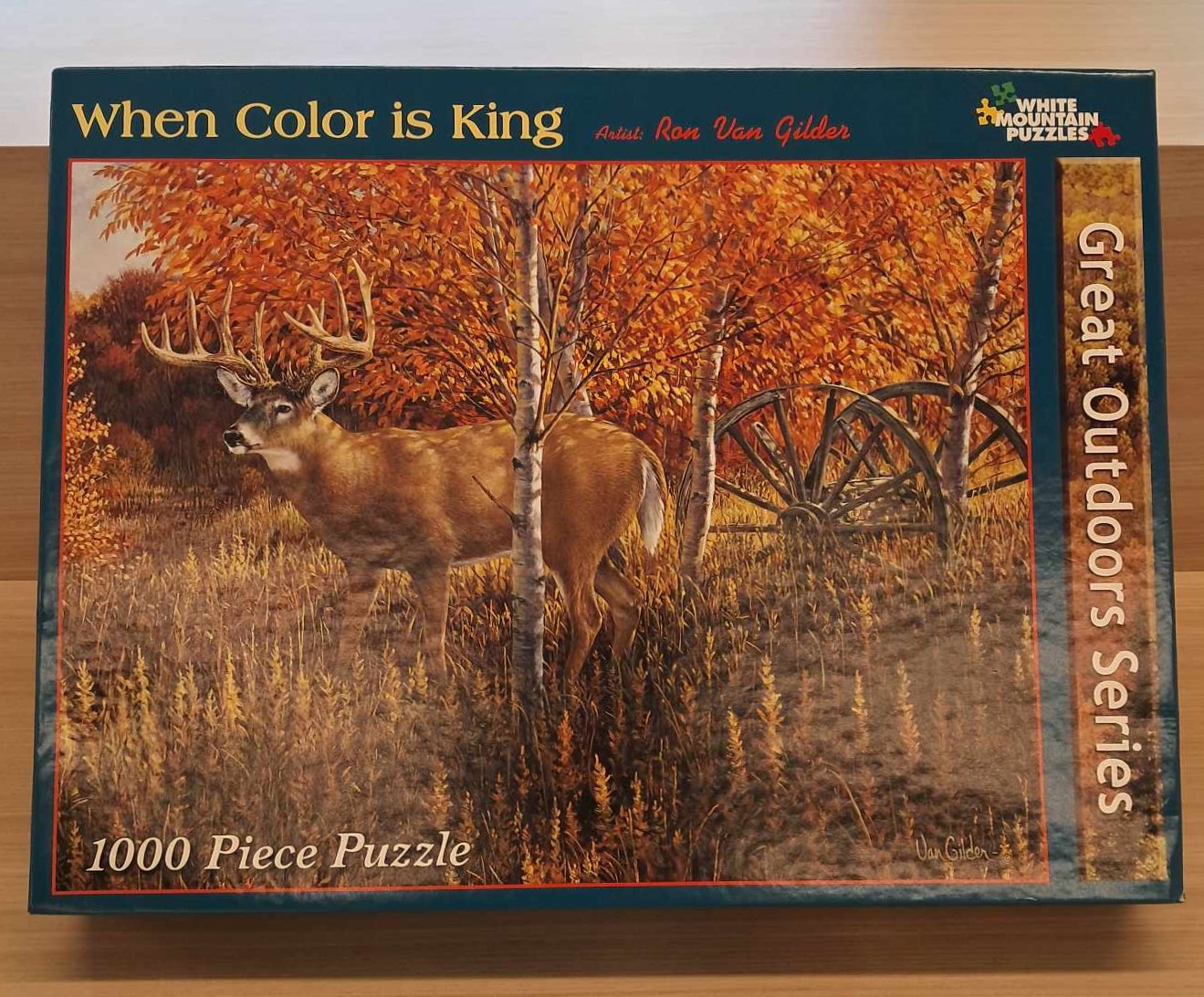 Puzzle cover of a Buck standing in a autumn forest next to some old wagon wheels.