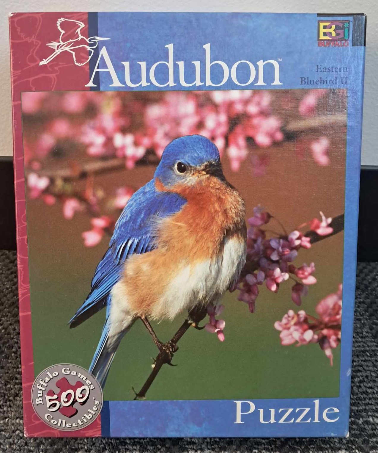 Image of a puzzle cover with a photograph of a bluebird perched on a cherry blossom branch.