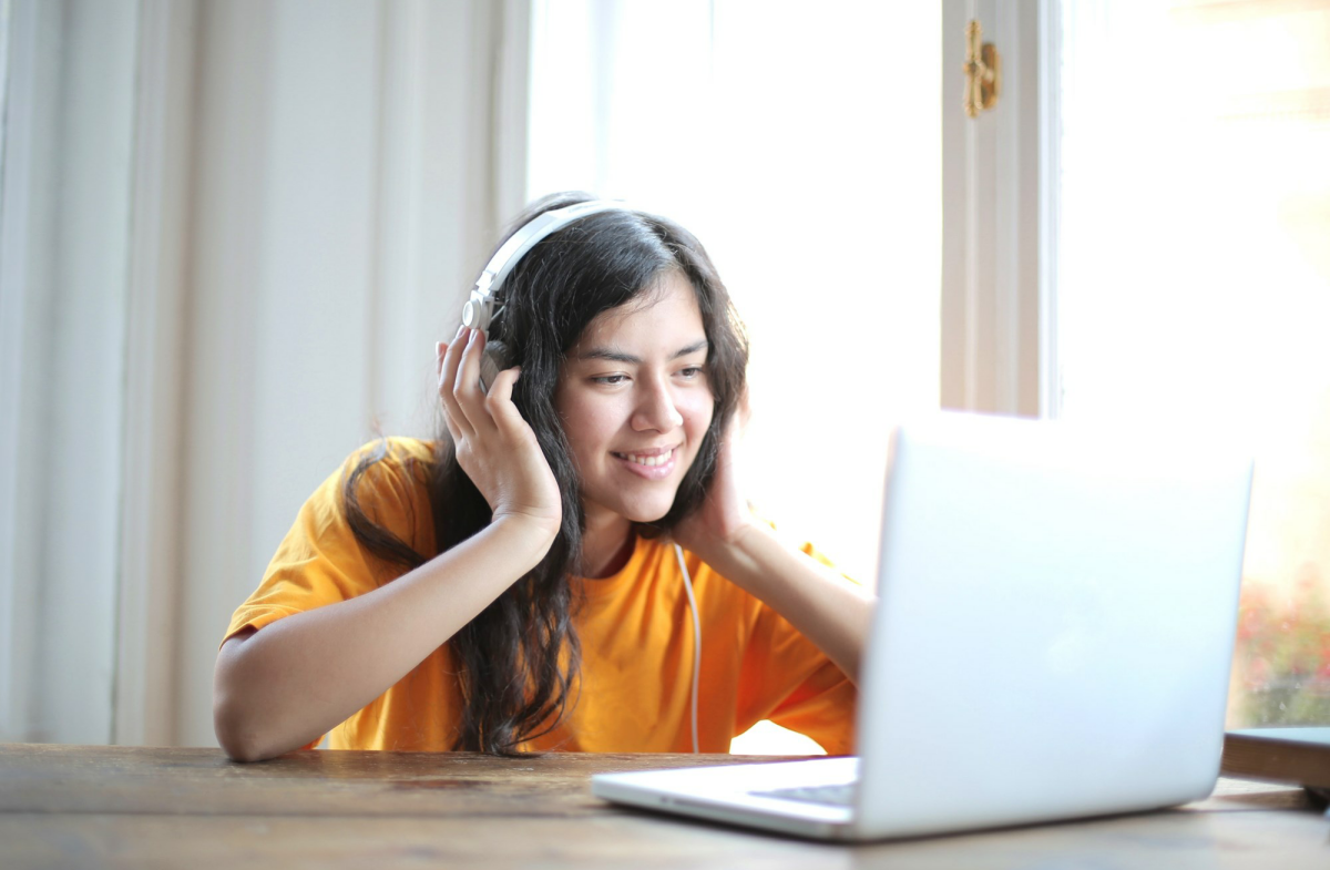 A young woman sitting in front of a computer wearing headphones.