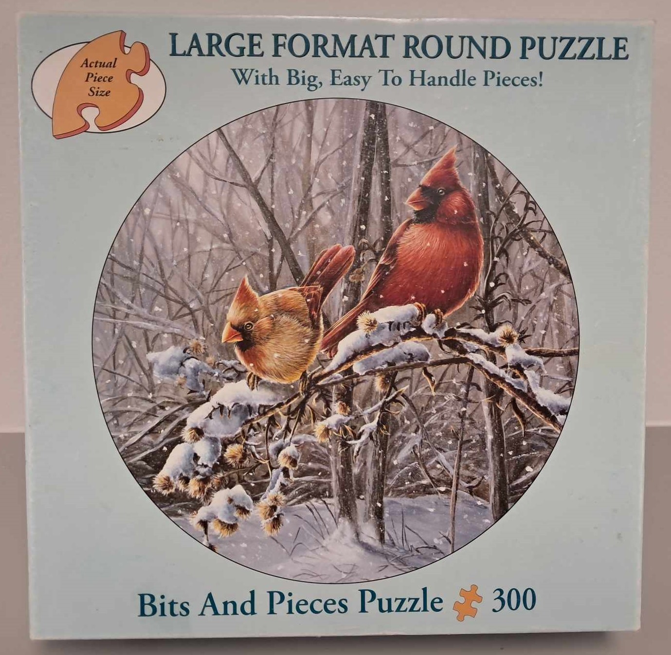 Image of a puzzle cover of an artistic drawing of redbirds perched on a snowy branch.