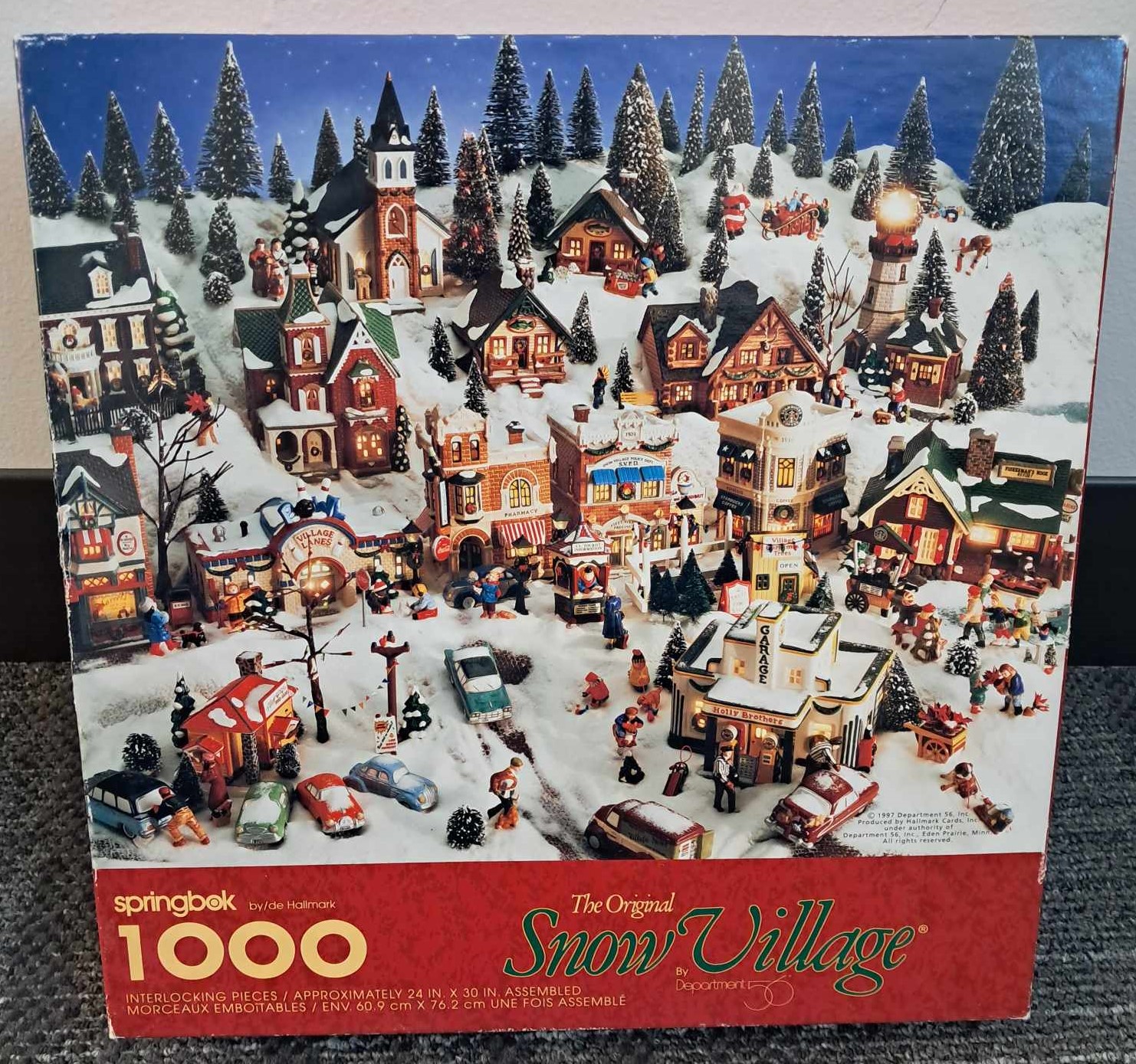 Image of a puzzle cover showing a snowy landscape made out of toy cars, houses, and pine trees.