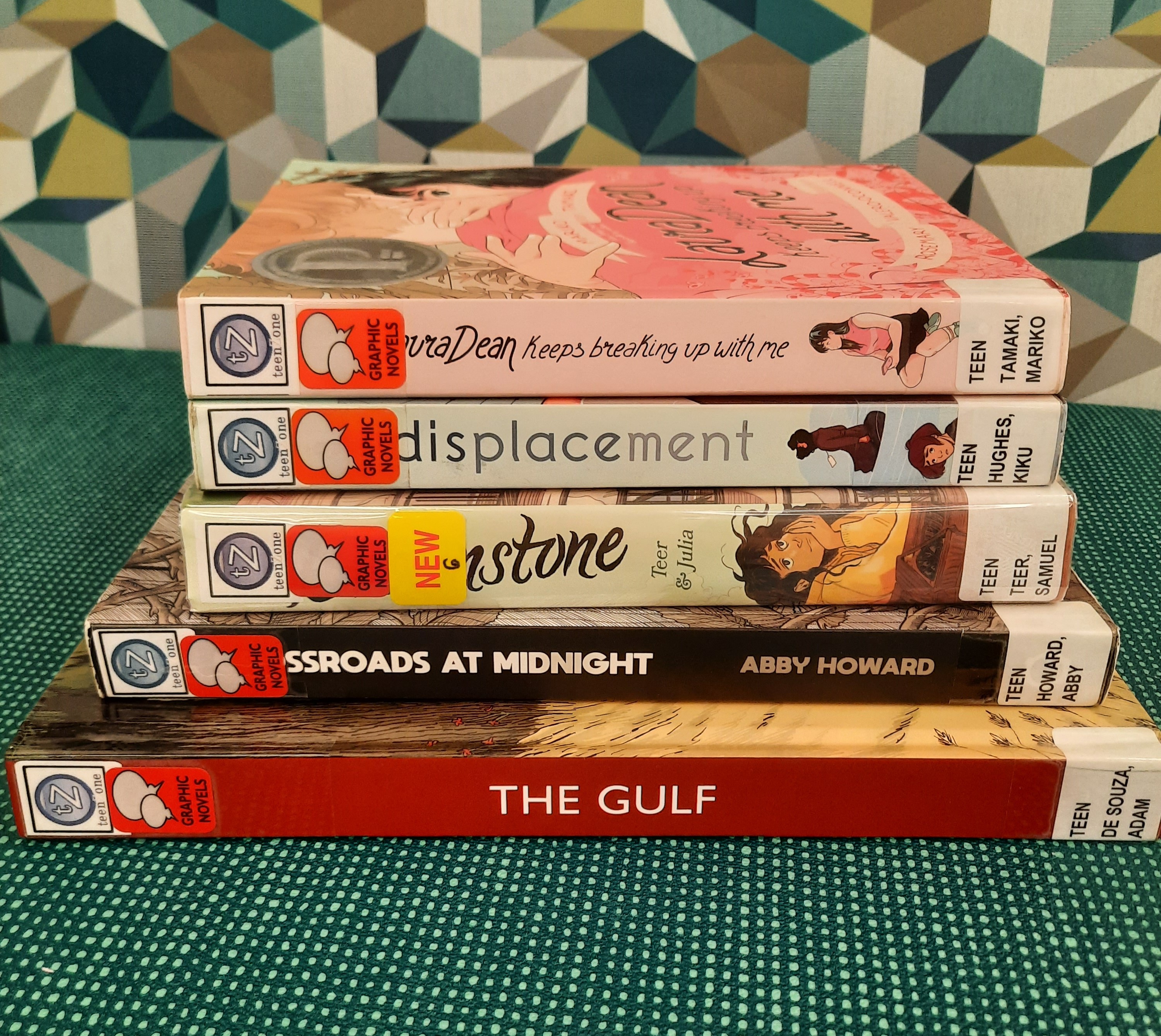 Book Stack showing the following titles: "Laura Dean Keeps Breaking up with me," "Displacement," "Brownstone," "Crossroads at Midnight," and "The Gulf"