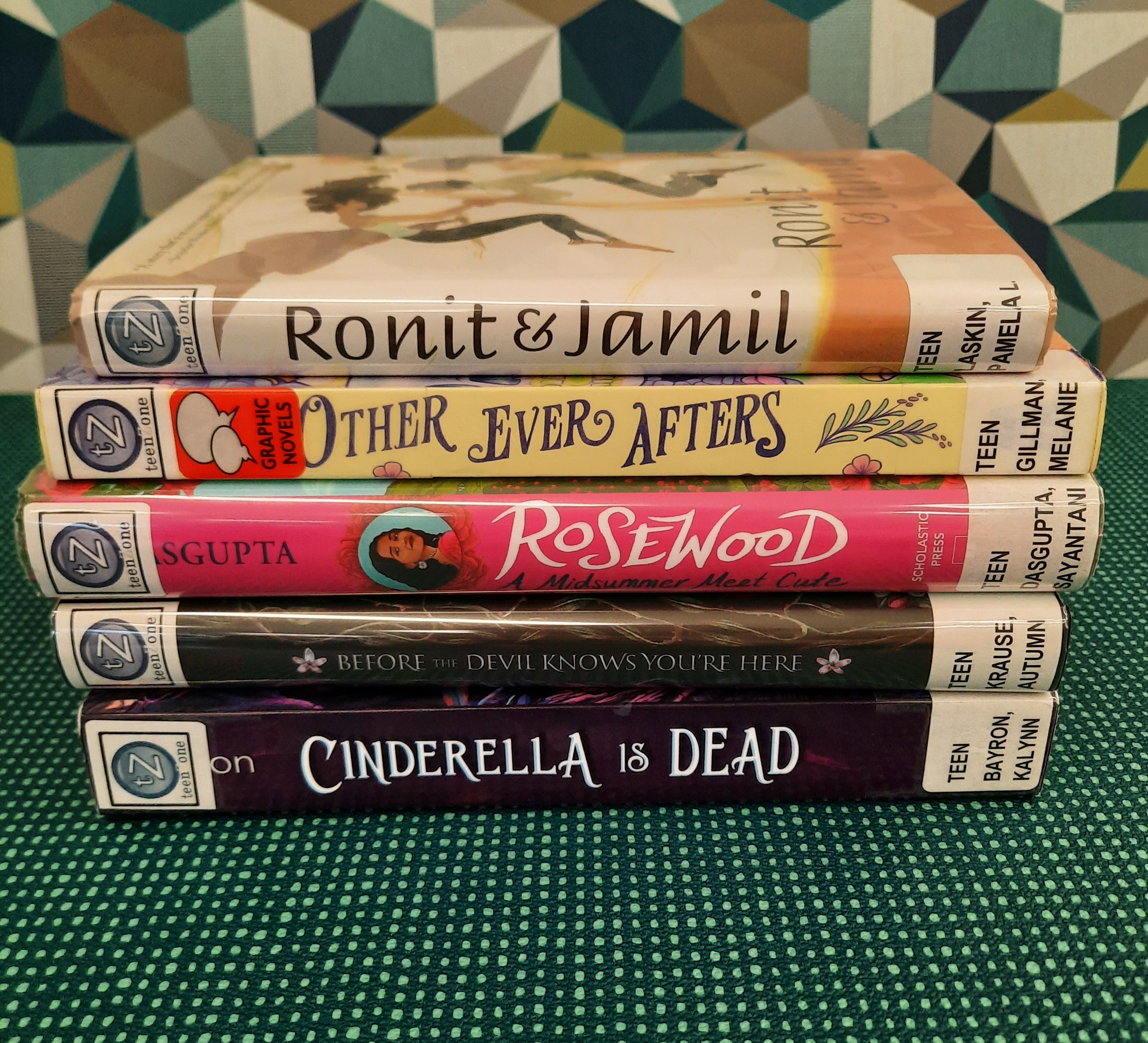 Book stack showing the following titles: "Ronit & Jamil," "Other Ever Afters," "Rosewood: A Midsummer Meet Cute," "Before the Devil Knows You're Here," and "Cinderella is Dead"