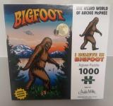 Image of a puzzle cover titled "I Believe in Bigfoot" that shows an illustrated rendering of Bigfoot walking through the forest by a lake near mountains.